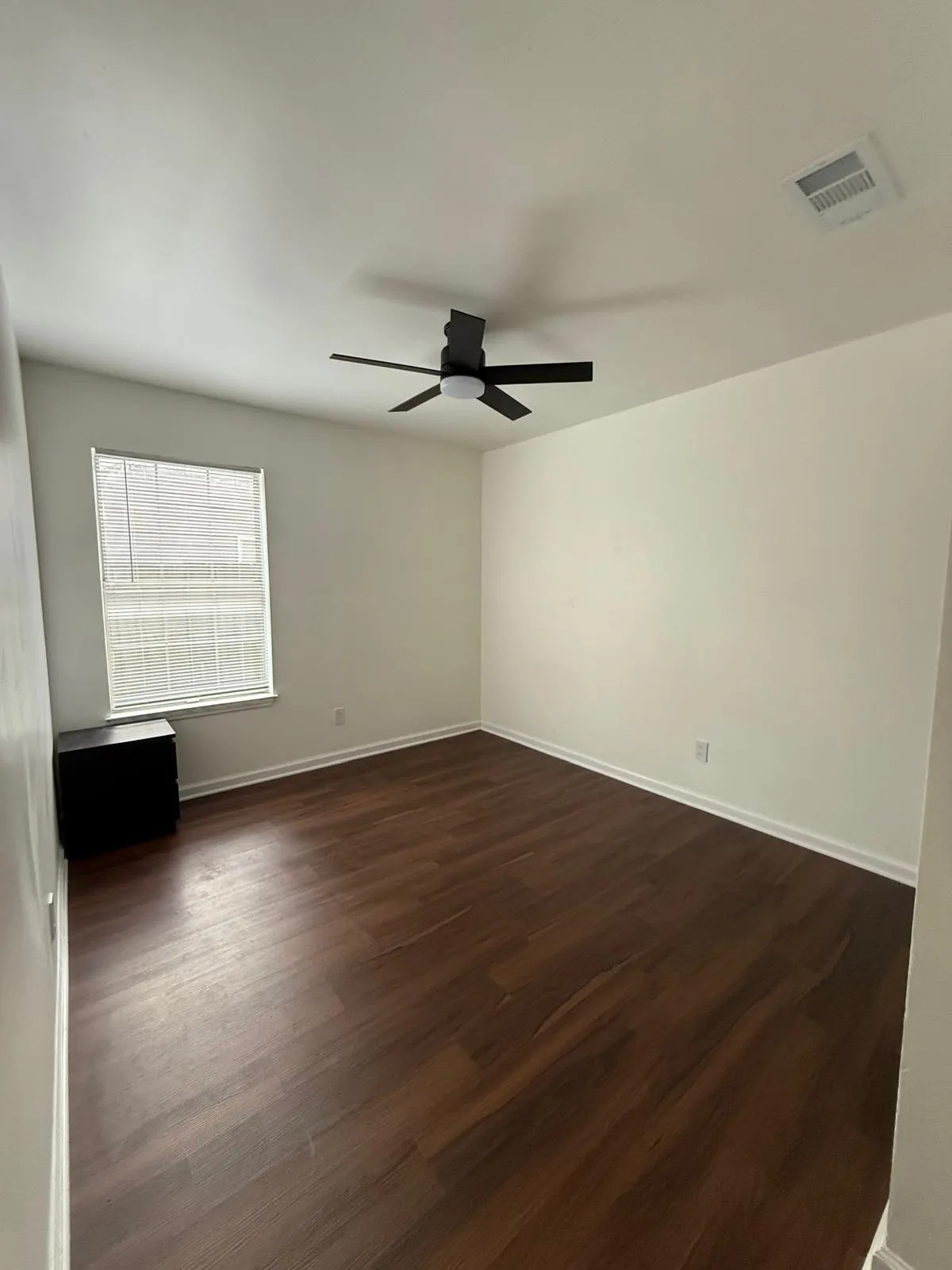 A bedroom with a new ceiling fan, fresh paint and replaced flooring.