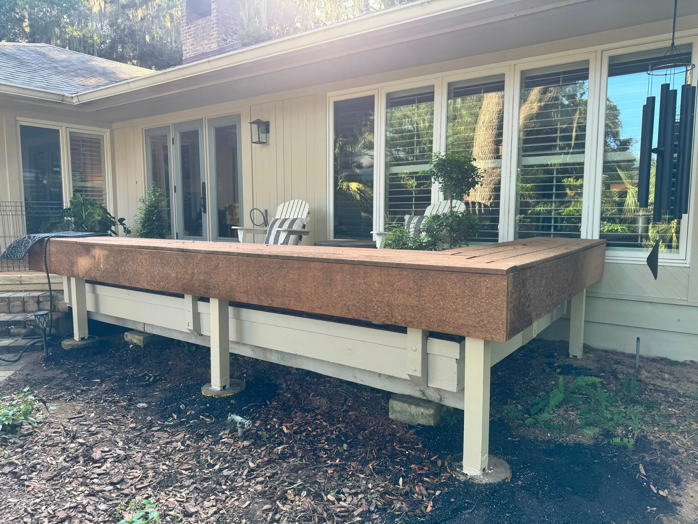 The deck bench running the length of the house below a wall of windows, re-supported and levelled.