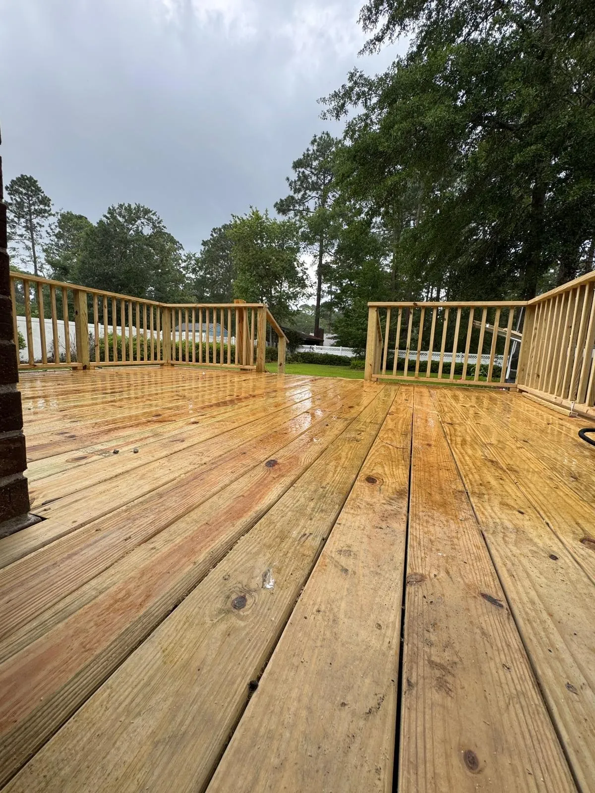 A newly built timber deck with turned railings, looking out across the garden.