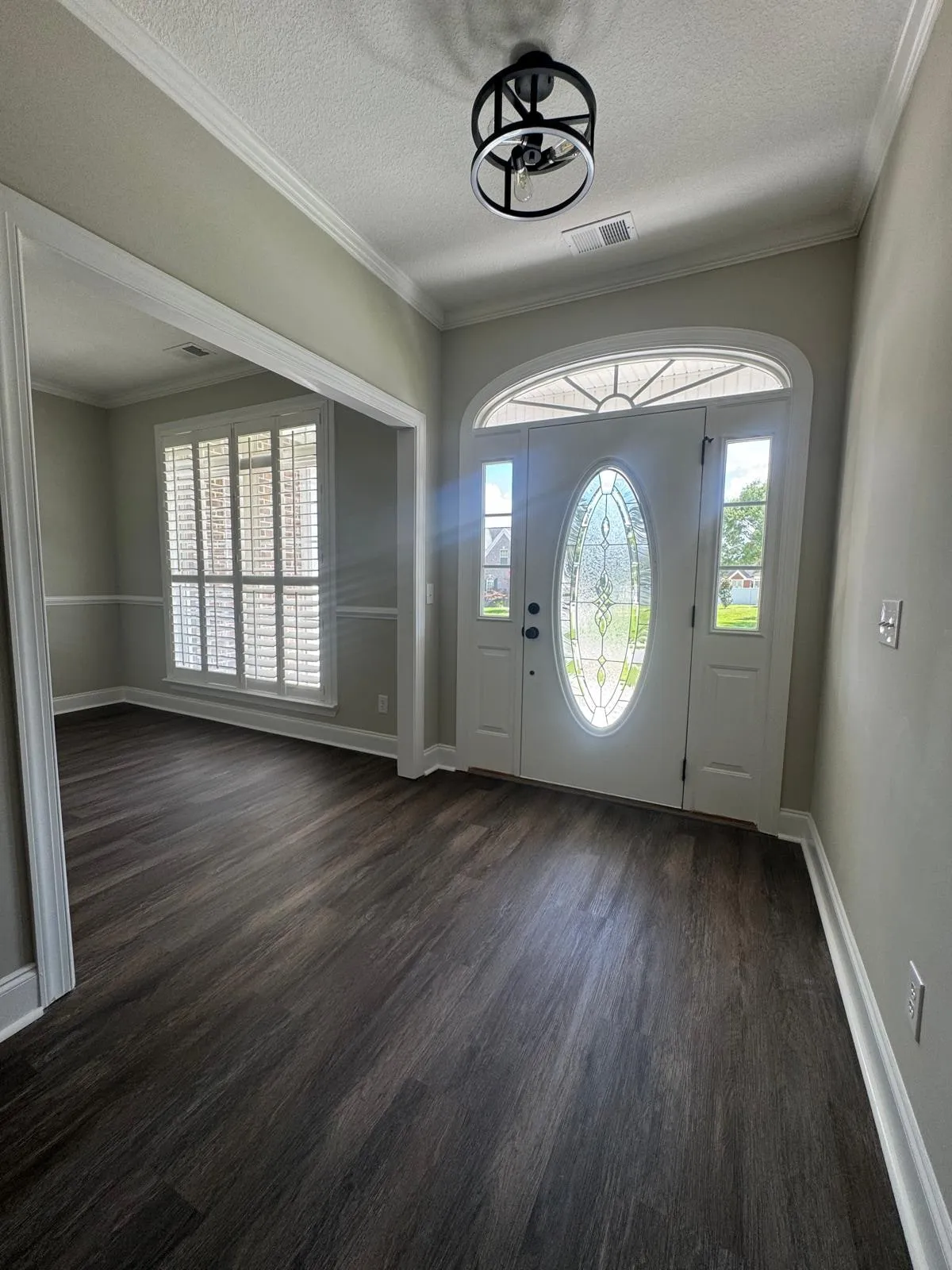 An entry hall after redecoration, with an arched fanlight over the door and new plank flooring.