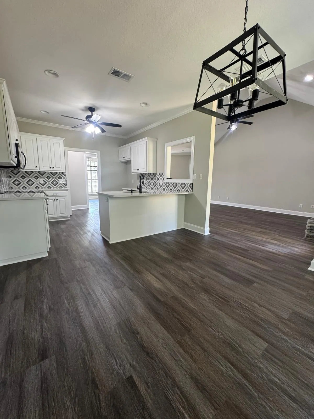 A kitchen and dining area with white cabinetry, patterned splashback and new plank flooring.