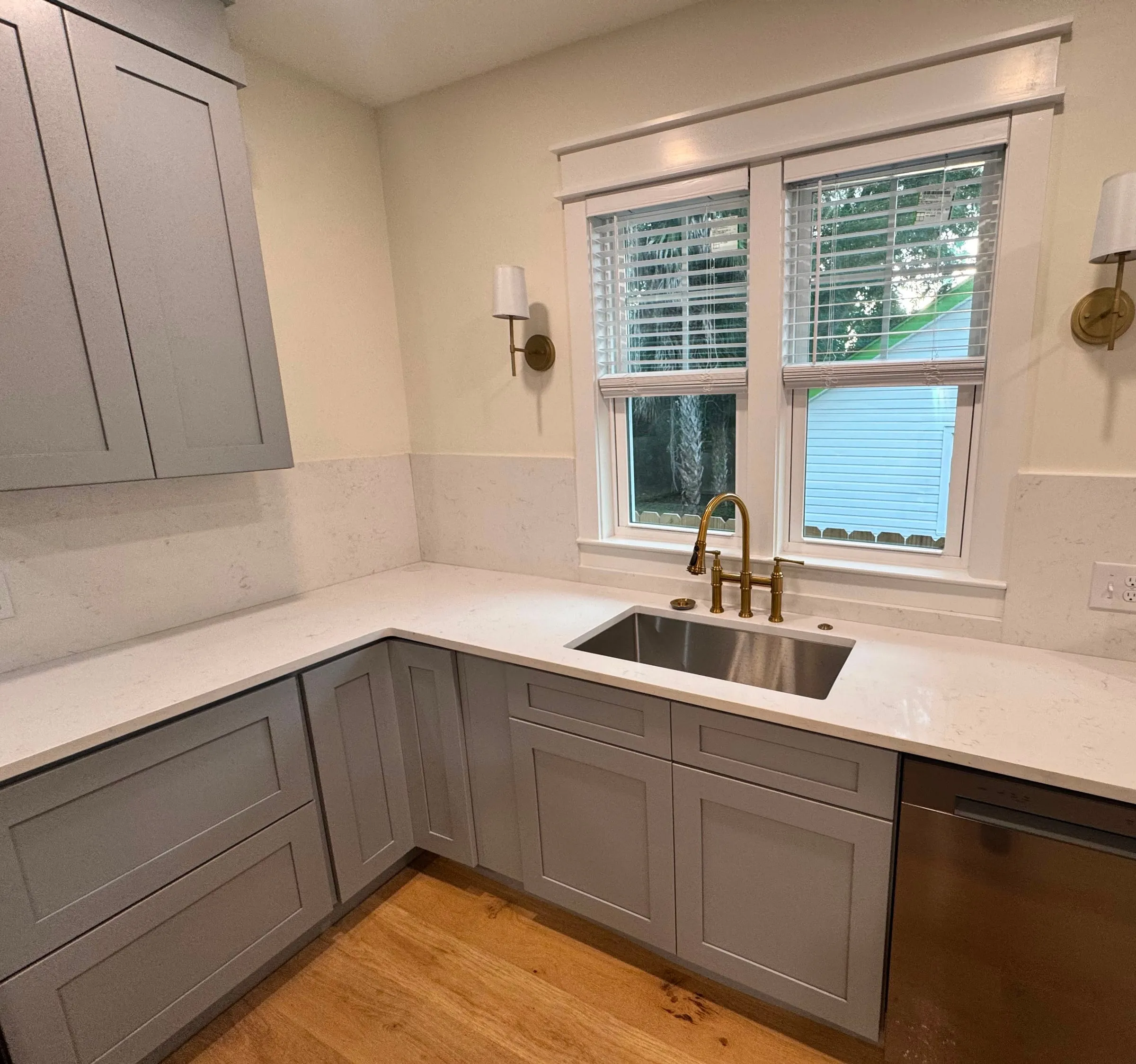 The kitchen sink run beneath a double window, with quartz worktops and brass fittings.