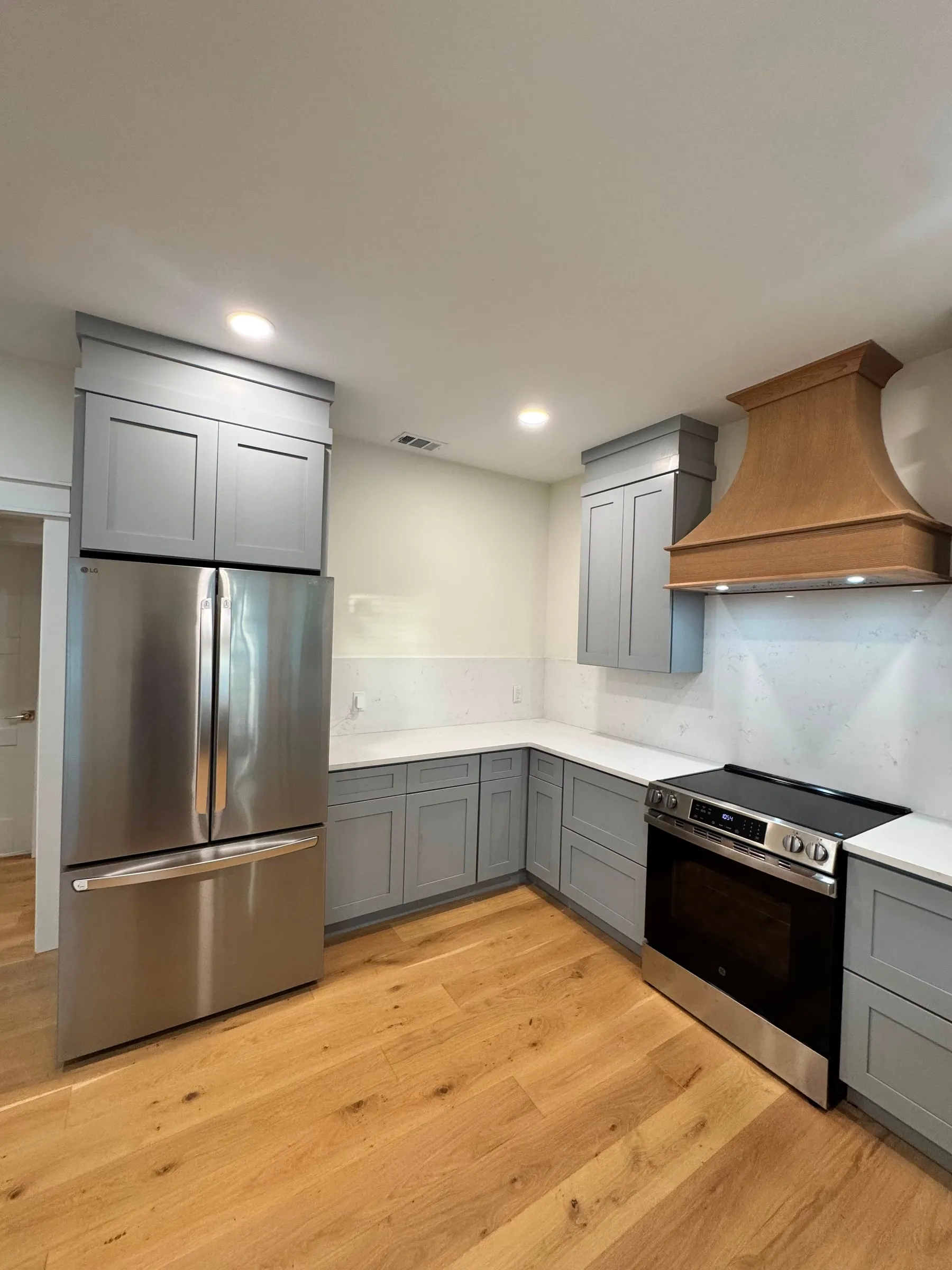 The kitchen range wall, with grey shaker cabinetry and a tapered timber hood.