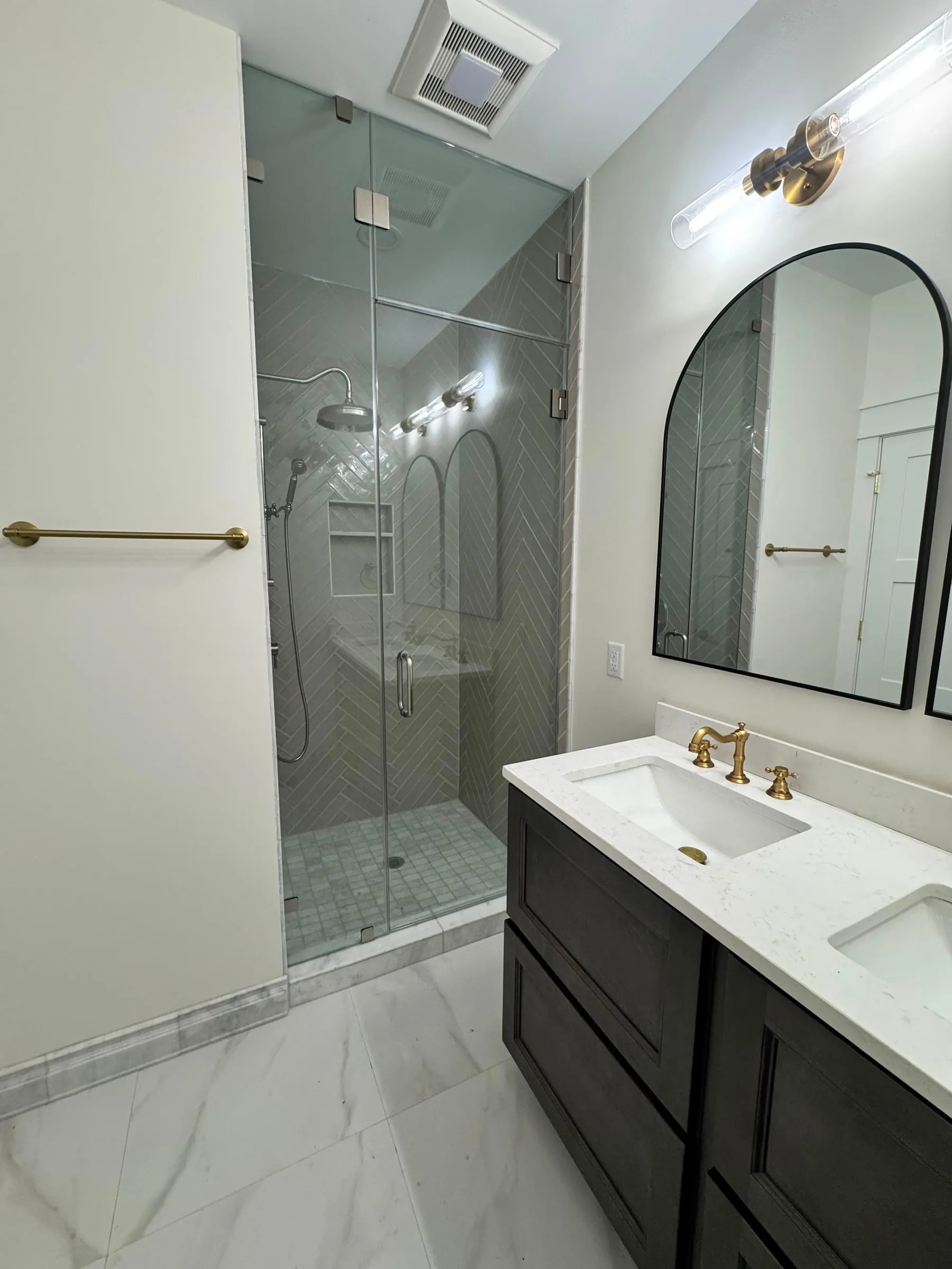 The primary bathroom, with a glazed walk-in shower in herringbone tile and a double vanity.