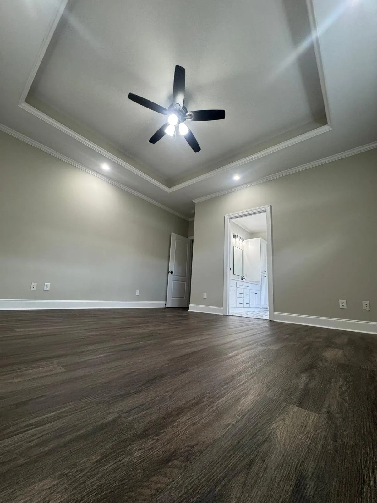 A primary bedroom with a tray ceiling, fresh paint and new flooring.