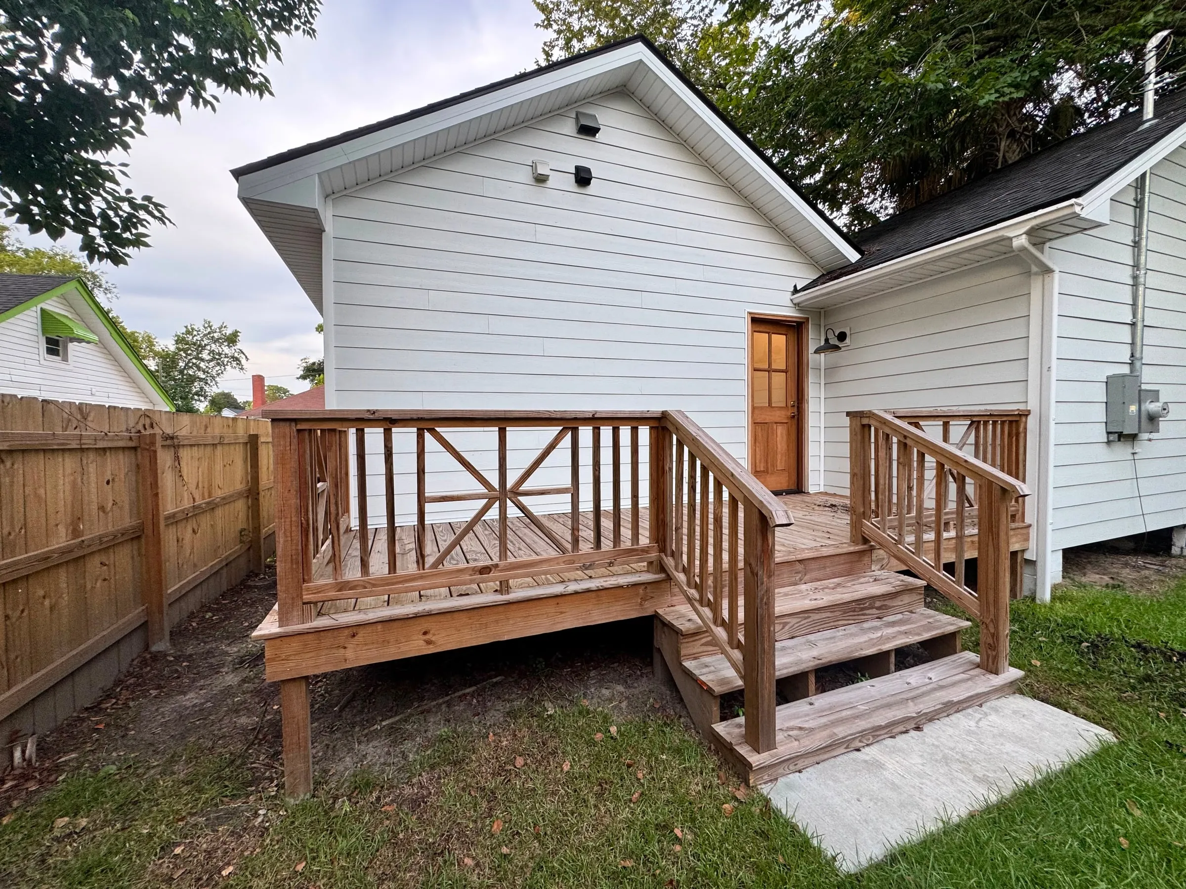 The rear elevation and new timber deck, with X-braced railings and steps down to the garden.