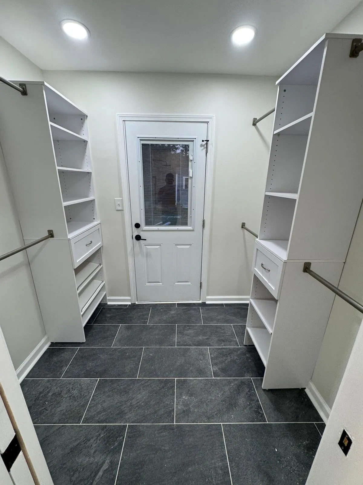 A custom walk-in closet with fitted shelving and hanging rails to both sides.